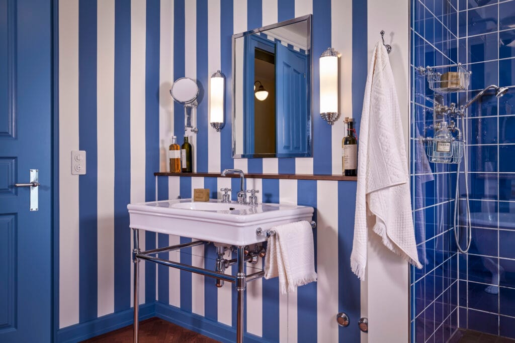Blaues Badezimmer im Art-Deco Stil mit hochwertigen Accessoires massivem Spiegel und Duscharmaturen